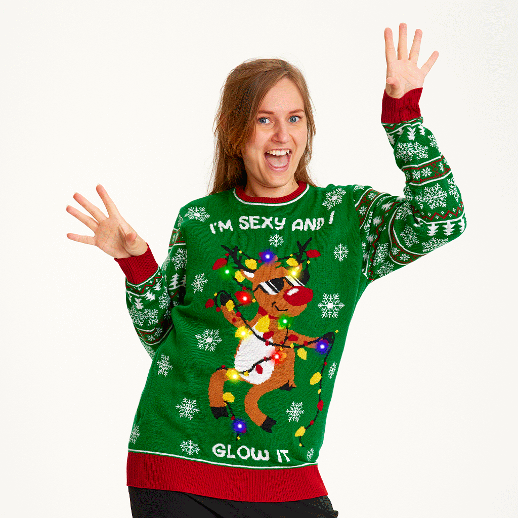 Une femme portant un pull de Noël vert avec un renne dansant et des lumières.